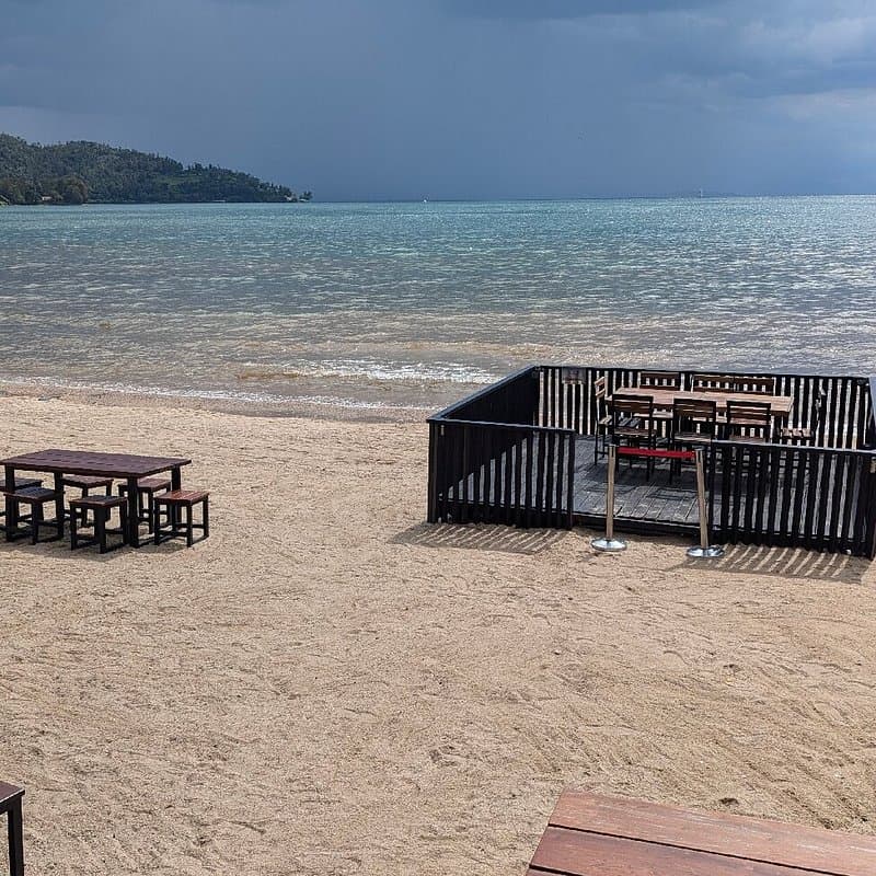 Tables on the sand and a deck built out over the water